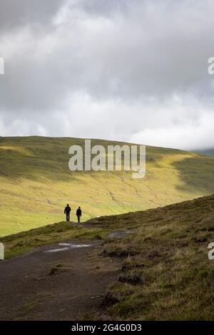 Two hikers walking the Traelanipa trail along lake Sorvagsvatn on the island of Vagar in the Faroe Islands Stock Photo