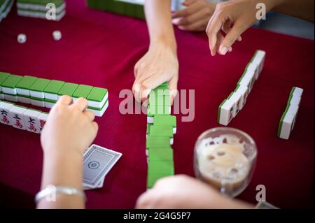 People playing mahjong traditional Chinese board game on a red table at home Stock Photo