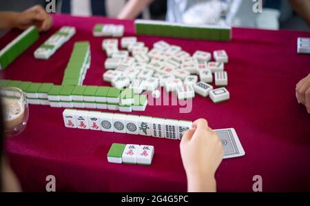 People playing mahjong traditional Chinese board game on a red table at home Stock Photo