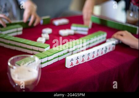 People playing mahjong traditional Chinese board game on a red table at home Stock Photo