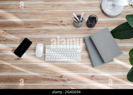 Computer keyboard, mouse, smartphone and books on office table, view from above Stock Photo