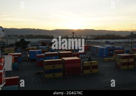 Unloading shipping containers at sunset from Cargo Ship silhouetted in ...