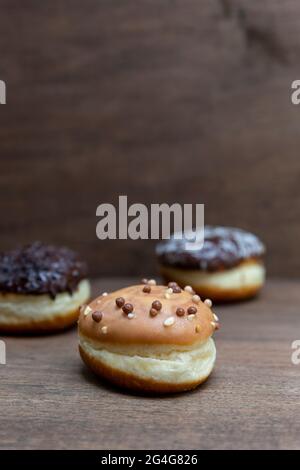 Delicious glazed chocolate donuts on wooden background Stock Photo