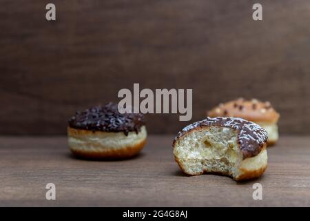 Delicious glazed chocolate donuts on wooden background Stock Photo