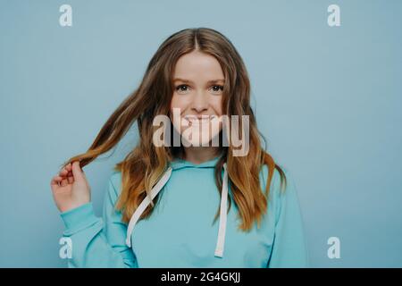 Blue haired Teenage girl in blue hoodie staying near graffiti wall with red water  bottle Stock Photo by katrinshine