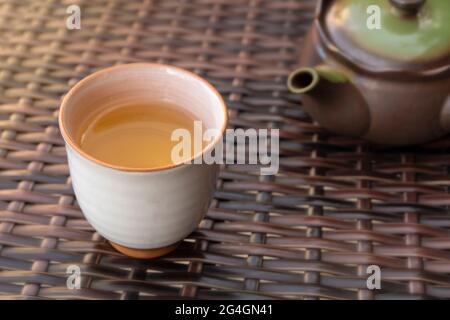 Hand pouring healthy hot herbal tea in a ceramic cup outside in a cafe or restaurant Stock Photo