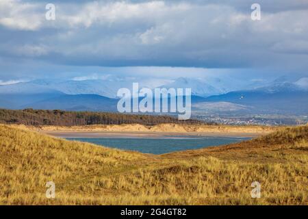 Newborough Beach and sand dunes from Llanddwyn Island with the snow covered mountains of Snowdonia in the background, Anglesey, North Wales Stock Photo