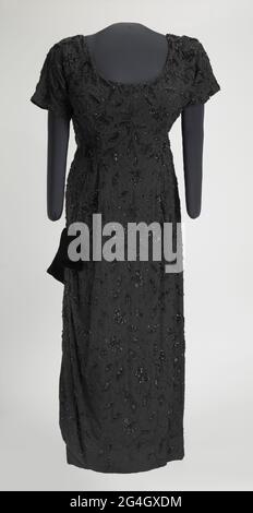 Ella Jane Fitzgerald (1917-1996) was an African-American jazz singer, sometimes referred to as the First Lady of Song, Queen of Jazz, and Lady Ella. The dress is made from black synthetic crepe fabric that is hand beaded with black glass seed and bugle beads, and black sequins in a floral vine design. The bodice is short-sleeved and has a scoop neck in the front and a V-neck in the back. There is a metal zipper in the center back that goes to the hip, and a hook-and-eye at the top of the zipper. The gown has a princess cut waist, but there is no seam at the waist. The gown has a column skirt w Stock Photo