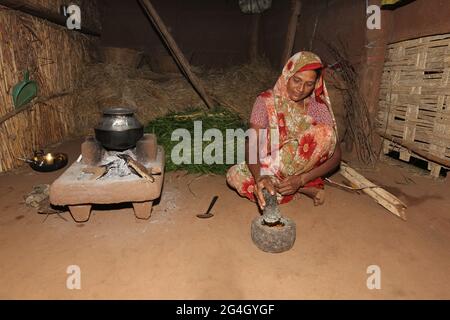 DHANKA TADVI TRIBE. Tadvi bhil woman using Pestle and Mortar for making chilly chuatney at Mogarapani Village in Akkalkuwa tehsil of Nandurbar Dist in Stock Photo