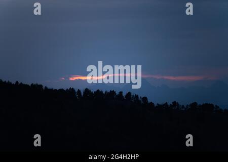 Landscape with dark misty silhouettes of alpine mountains and fir trees forest in Pyrenees. Stock Photo