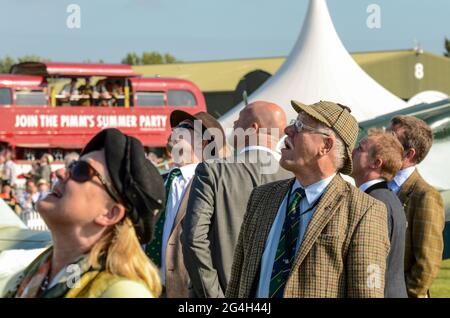 Visitors in vintage attire looking up at the flying display at the Goodwood Revival vintage event, West Sussex, UK. People in period costumes Stock Photo