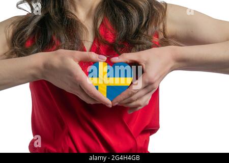 Love Sweden. The woman holds a heart in the form of the flag of Sweden on her chest. Concept of patriotism. Stock Photo