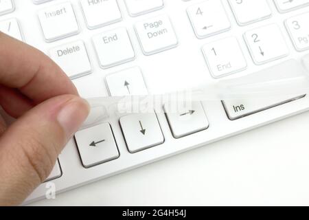 The hand removes the silicone film from the keyboard that protects it from dust and dirt. Keyboard save. Stock Photo