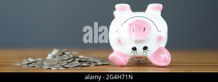 Coins and an upside down piggy bank lie on table Stock Photo
