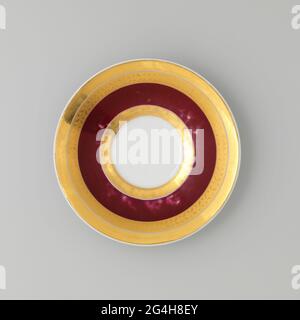 Dish, purple red fond with golden piping. Dish of porcelain, part of a coffee set, with purple red fond and golden piping along the edge a wide golden trim in which a engraved leaf drink. No brand. Stock Photo