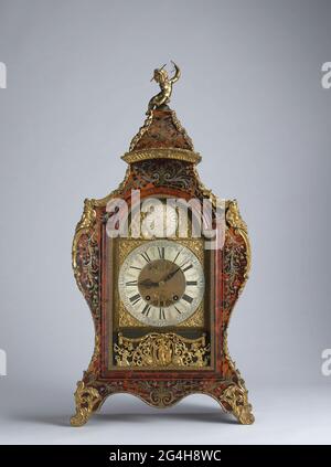 . Table clock or console clock of oak, veneered with copper marqueterie and tin on a tortoise fond on red mug, and with gold-plated bronze fittings. The cupboard has a vaulted bottom and curved sides. He rejuvenates upwards and is crowned by a removable cap. The cupboard has a straight window door in the front with a bright bow-shaped top edge, surrounded by a turtle profile edge, within which a cast copper edge with balusters and garlands. The engraved dial of white colored metal surrounded by four cast corner pieces with women's figures. In the lunet a round plate of white colored metal, eng Stock Photo