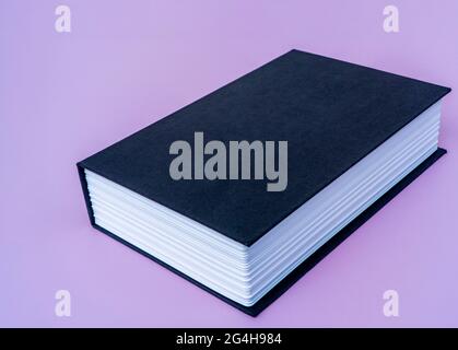 Big black book on violet isolated background with copy space for your text. High quality photo.  Stock Photo
