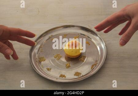 On a metal plate one last muffin. From different sides of the two hands are drawn to it. Stock Photo