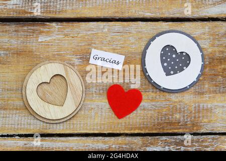 Gracias (thank you in Spanish) card with three hearts on rustic wooden surface Stock Photo