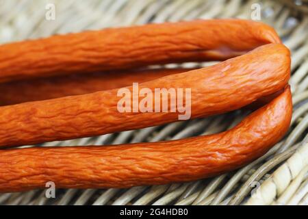 Traditional Polish smoked sausage called kabanos on wicker surface Stock Photo