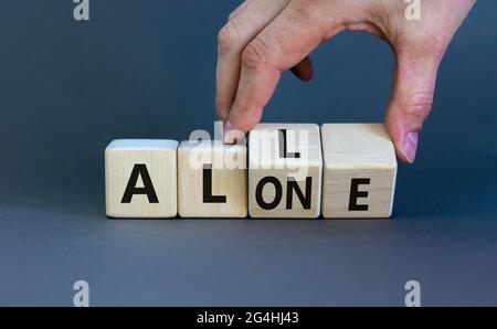 All or alone and support symbol. Businessman turns the wooden cube and changes the word alone to all. Beautiful grey background. Business and all or a Stock Photo