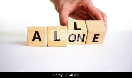 All or alone and support symbol. Businessman turns the wooden cube and changes the word alone to all. Beautiful white background. Business and all or Stock Photo