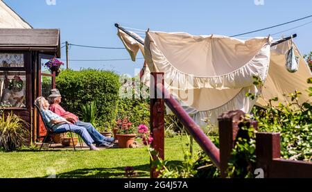 Couple on deckchairs, linen on laundry line in garden, The Lizard, Cornwall Stock Photo