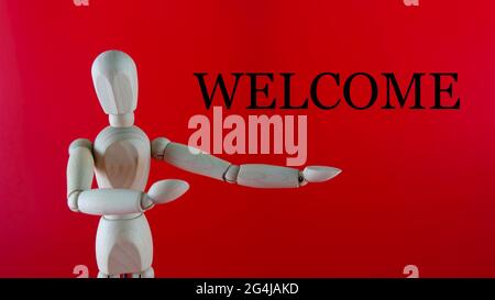 Selective focus a doll showing a sign to welcome visitor, customer, patients. Welcome text isolated on the red backgound. Welcome Concept Stock Photo