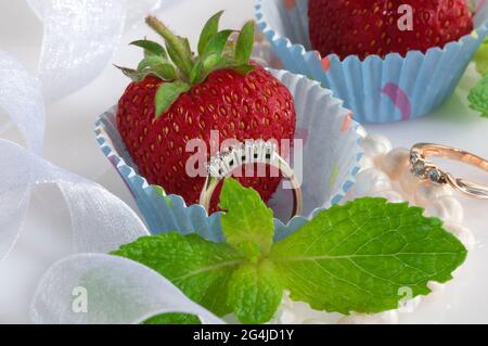 Jewelry set with diamonds in a paper cupcake mold with a juicy strawberry inside. Stock Photo
