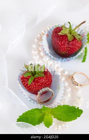 Jewelry set with diamonds in a paper cupcake mold with a juicy strawberry inside. Stock Photo