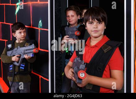 boy aiming laser gun at other players during lasertag game Stock Photo