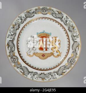 . Porcelain plate, painted on the glaze in blue, red, pink, black and gold. On the flat the arms of the Herzeele family. The weapon consists of two fields: on the left a red background with a golden twill, right 1. A gold ring with four red hearts, 2. a red background with two crossed knots, 3. Three black vulture swifts. The helmet sign is a crown and the weapon is worn by a lion and a griffin, standing on golden pedestal in Louis XIV style. To the weapon flower drinks in Bianco Sopra Bianco. A Spearhead border on the wall. The edge with an adornment in the Viennese du Paquier style with flow Stock Photo