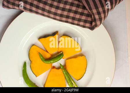 Pumpkin slice in wooden bowl isolated on white background with clipping path. Top view with copy space for your text. Flat lay Stock Photo