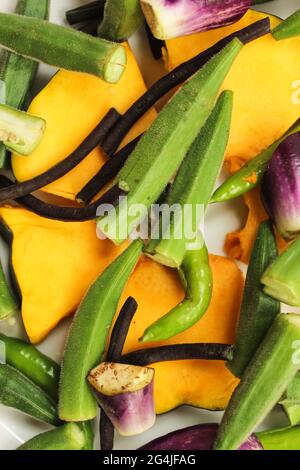 Mixed vegetables,pumpkin and ladyfinger and yardlong bean pieces mixed on white plate,top view Stock Photo