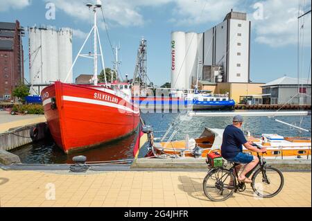 Fehmarn, Germany. 20th June, 2021. The multi-purpose vessel 'Jeanny' and the 'MS Silverland' are moored in a pier in the municipal port of Burgstaaken in front of silos for feed and fertilizer. The harbour basin is to be dredged to a depth of five metres to make the small harbour competitive again. (to dpa 'Fehmarn wants to deepen Burgstaaken municipal harbour') Credit: Gregor Fischer/dpa/Alamy Live News Stock Photo