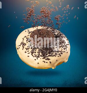 Flying donuts with glaze, sprinkles and biscuits on blue background Stock Photo