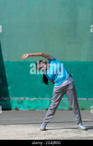 Energetic Hispanic female doing side bends in the open air Stock Photo