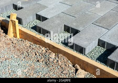 Gray stone pavers installation. Pavers installed in a running bond pattern on a gravel base next to wooden formwork Stock Photo