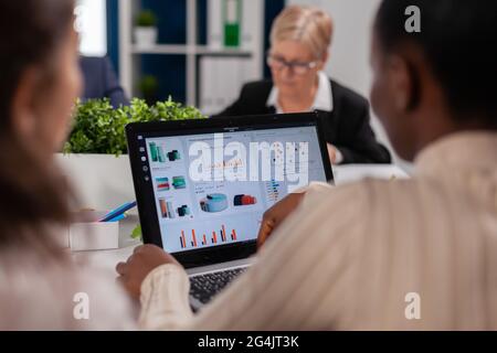 Focused executive manager working on annual financial report. Businesswoman discussing ideas with colleagues about financial strategy for new start up company working in brainstorming office. Stock Photo