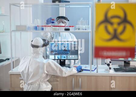 Team of scientist working to develope treatment for virus in lab dresed in ppe suit. Group of doctors examining vaccine evolution using high tech for diagnosis against covid19. Stock Photo