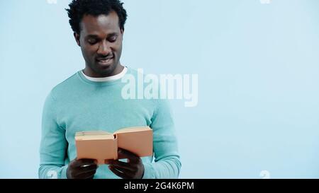 happy african american man reading book isolated on blue Stock Photo