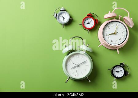 Different multicolor alarm clocks on green background Stock Photo