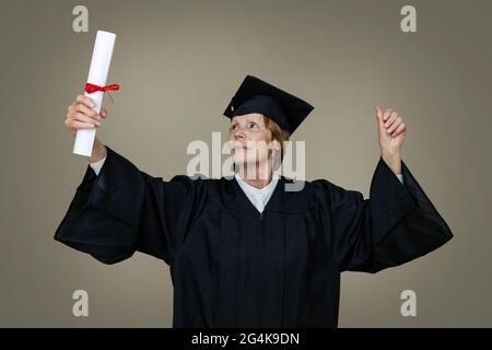 proud senior woman graduate in graduation gown and cap with college diploma Stock Photo