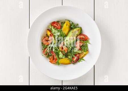 Salad of arugula, tomatoes, mango, avocado and shrimps with pesto Stock Photo