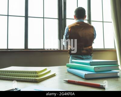 The man in the office looks out the window. The businessman is pondering. Stock Photo