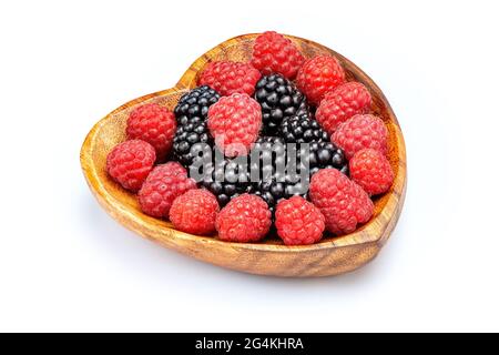 Raspberry and blackberry in wooden bowl in the shape of heart isolated on white background. Stock Photo