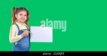 Banner, long format. Green background. A girl has in her hands a pen and a paper of white color, begins to write a word. Stock Photo