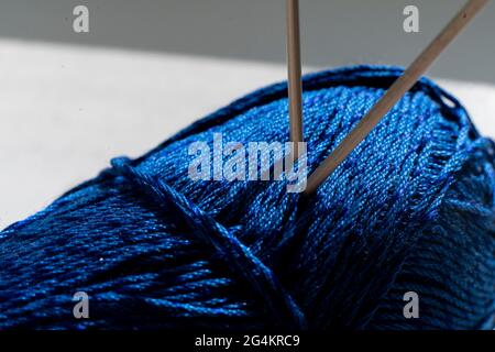 two twisted knitting needles inserted in the yarn roll, macro view Stock Photo