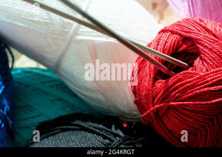 two twisted knitting needles inserted in the yarn roll, macro view Stock Photo