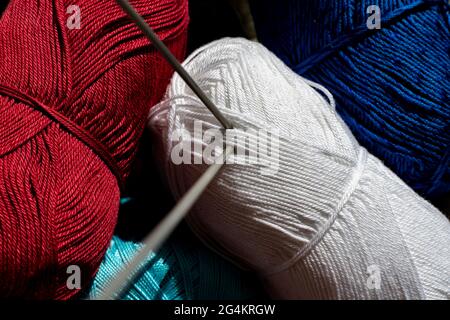 two twisted knitting needles inserted in the yarn roll, macro view Stock Photo